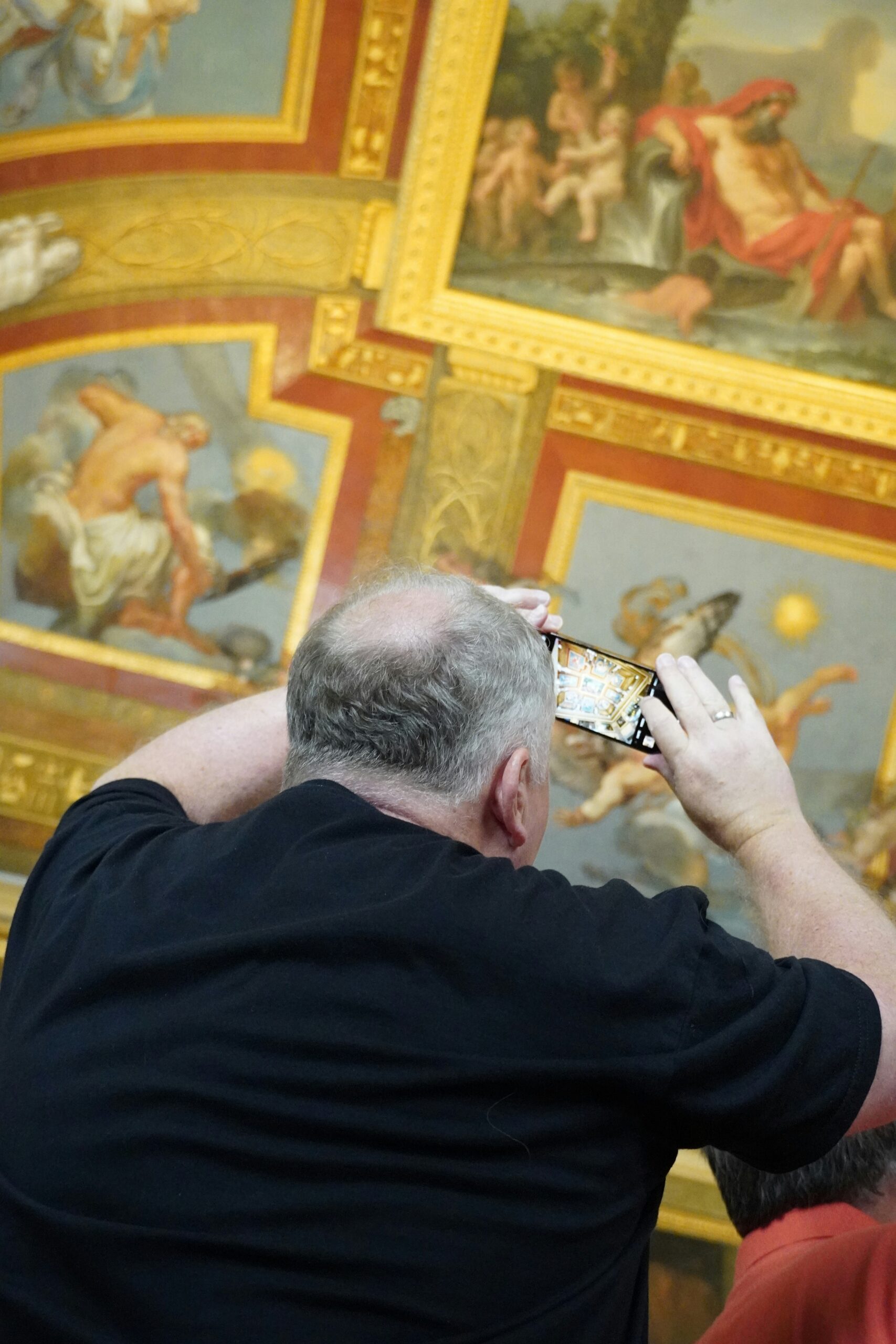 A man taking a picture of a ceiling with a cell phone